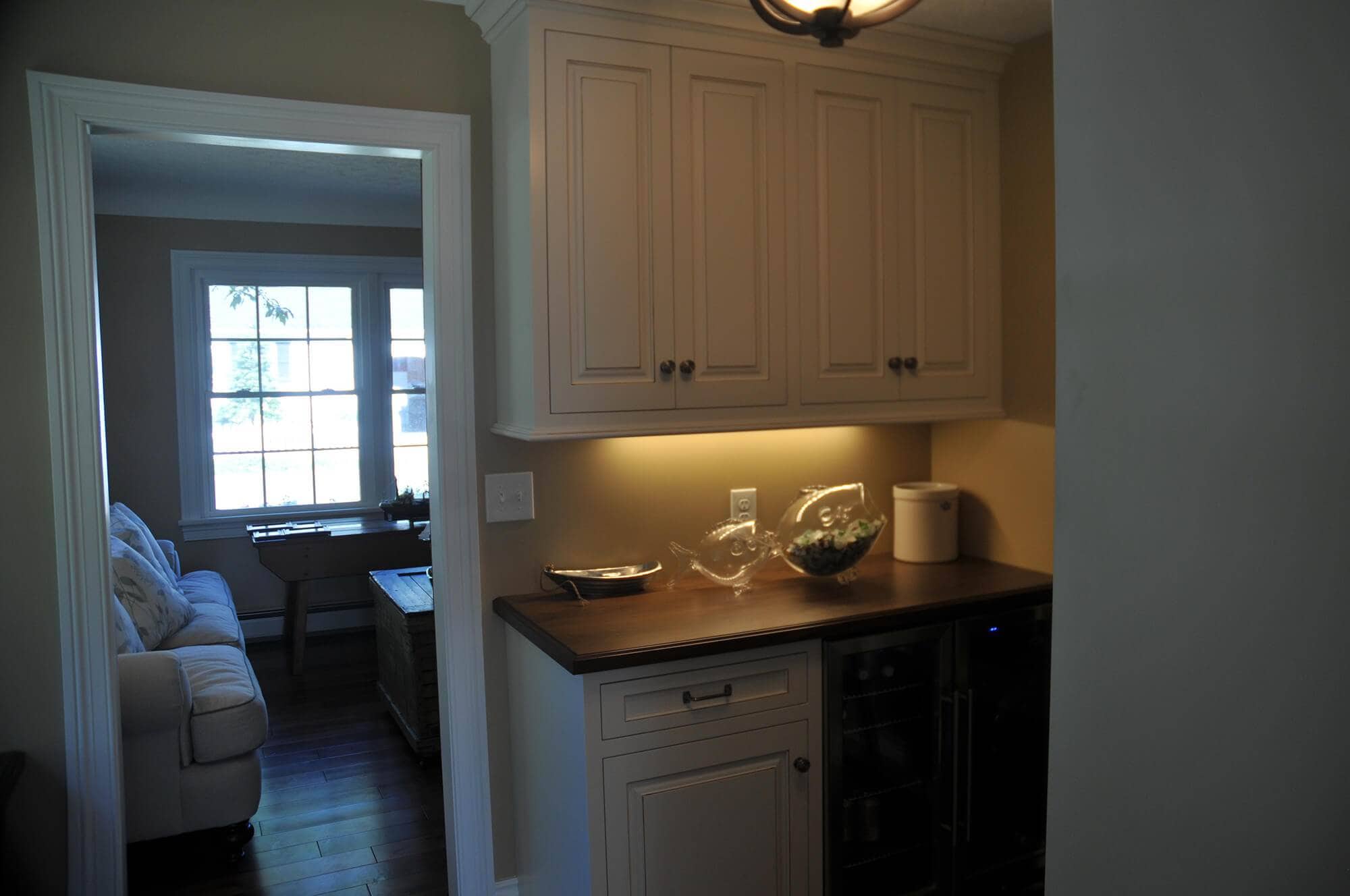 A kitchen with white cabinets and a refrigerator undergoing remodeling.