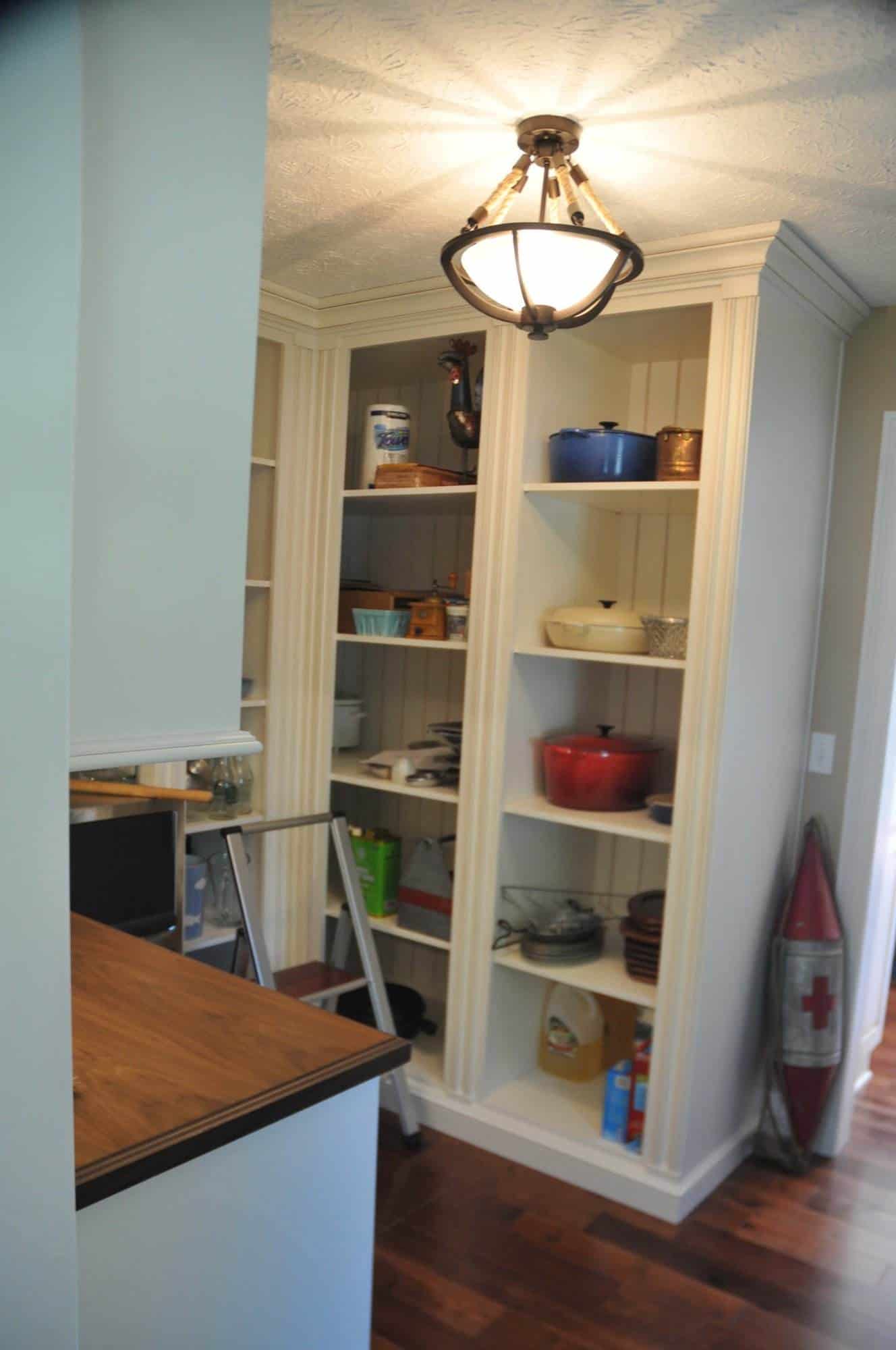 A kitchen with white cabinets and a wooden floor undergoing kitchen remodeling.