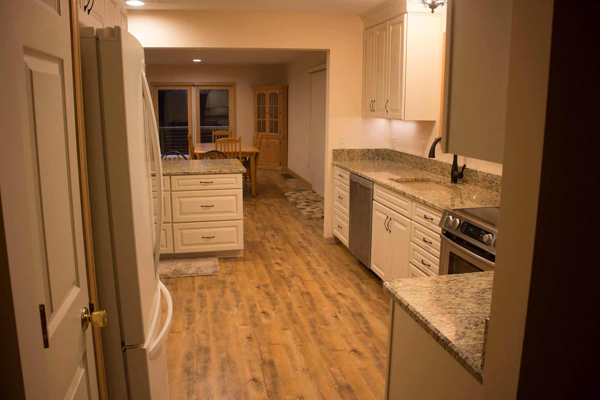A kitchen with wood floors and a refrigerator, perfect for home additions.