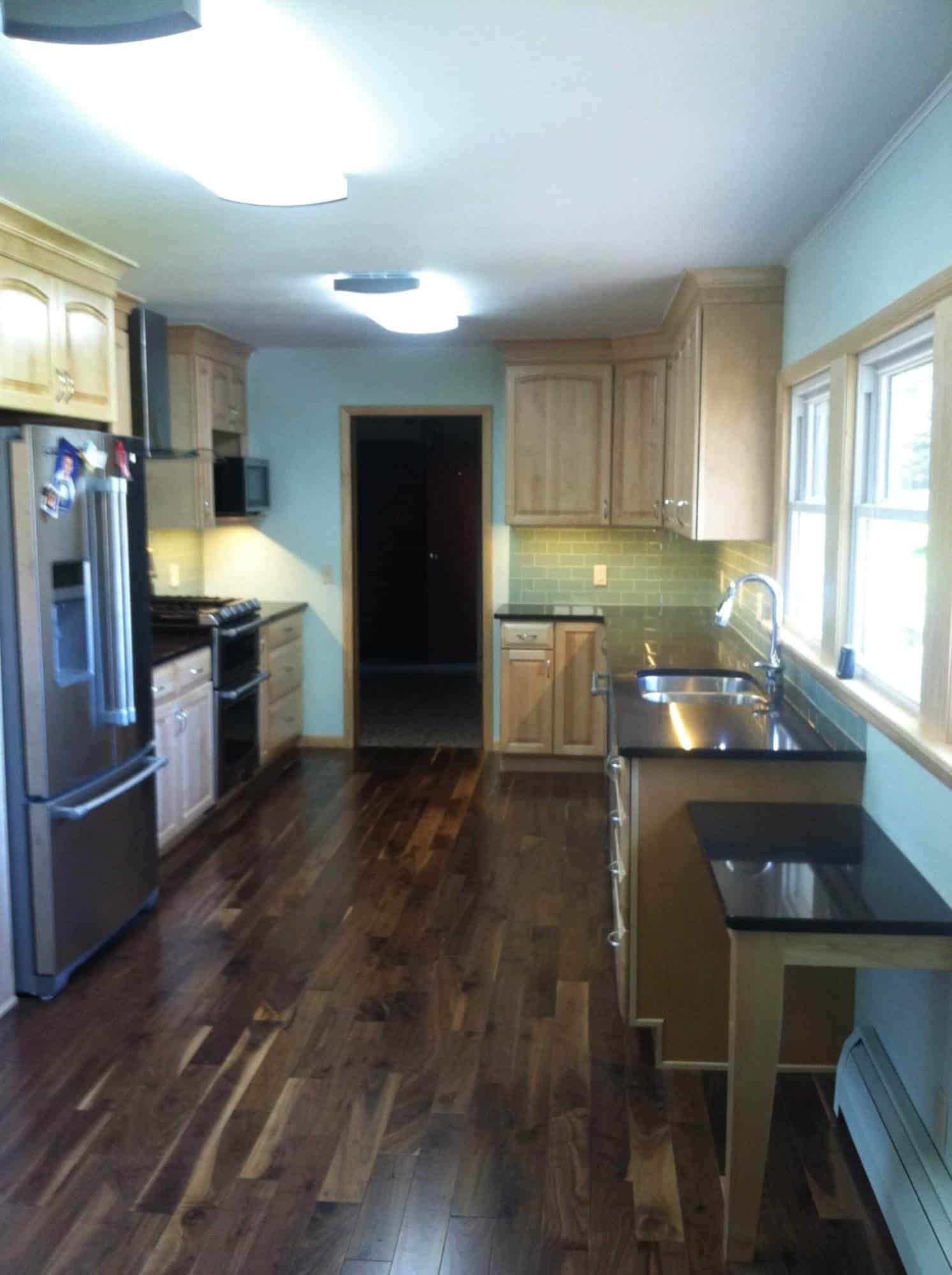 A kitchen undergoing remodeling with hardwood floors and stainless steel appliances.
