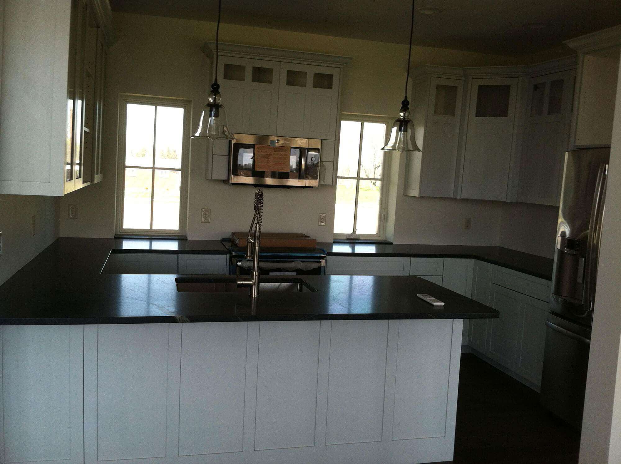 A new kitchen with a black counter top and stainless steel appliances in a newly built home.