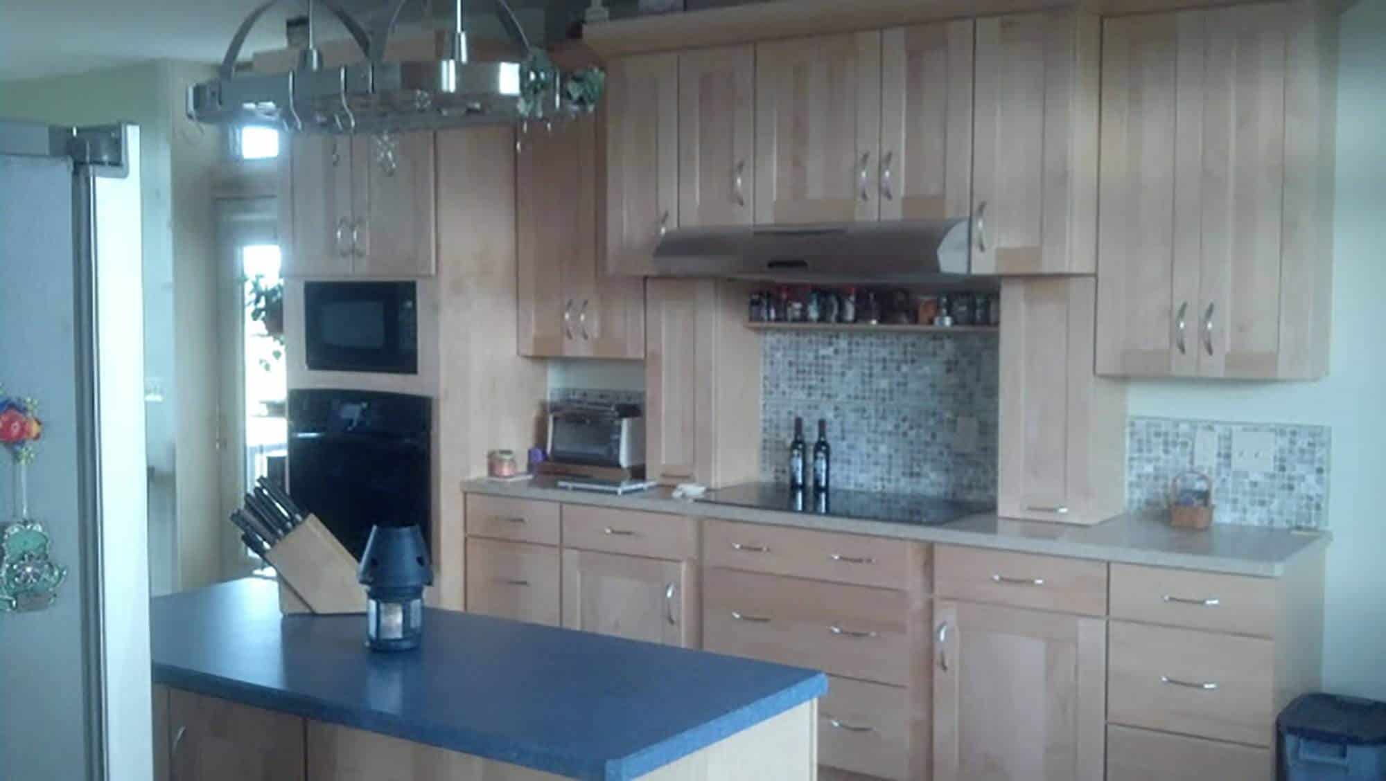 A new home kitchen with wood cabinets and a blue counter top.