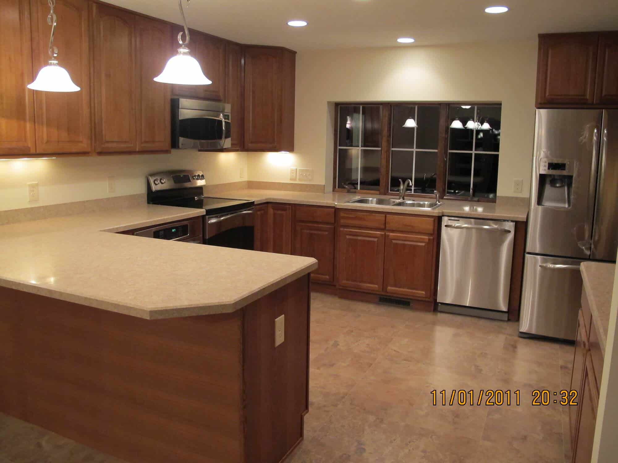 A newly built kitchen with brown cabinets and stainless steel appliances.