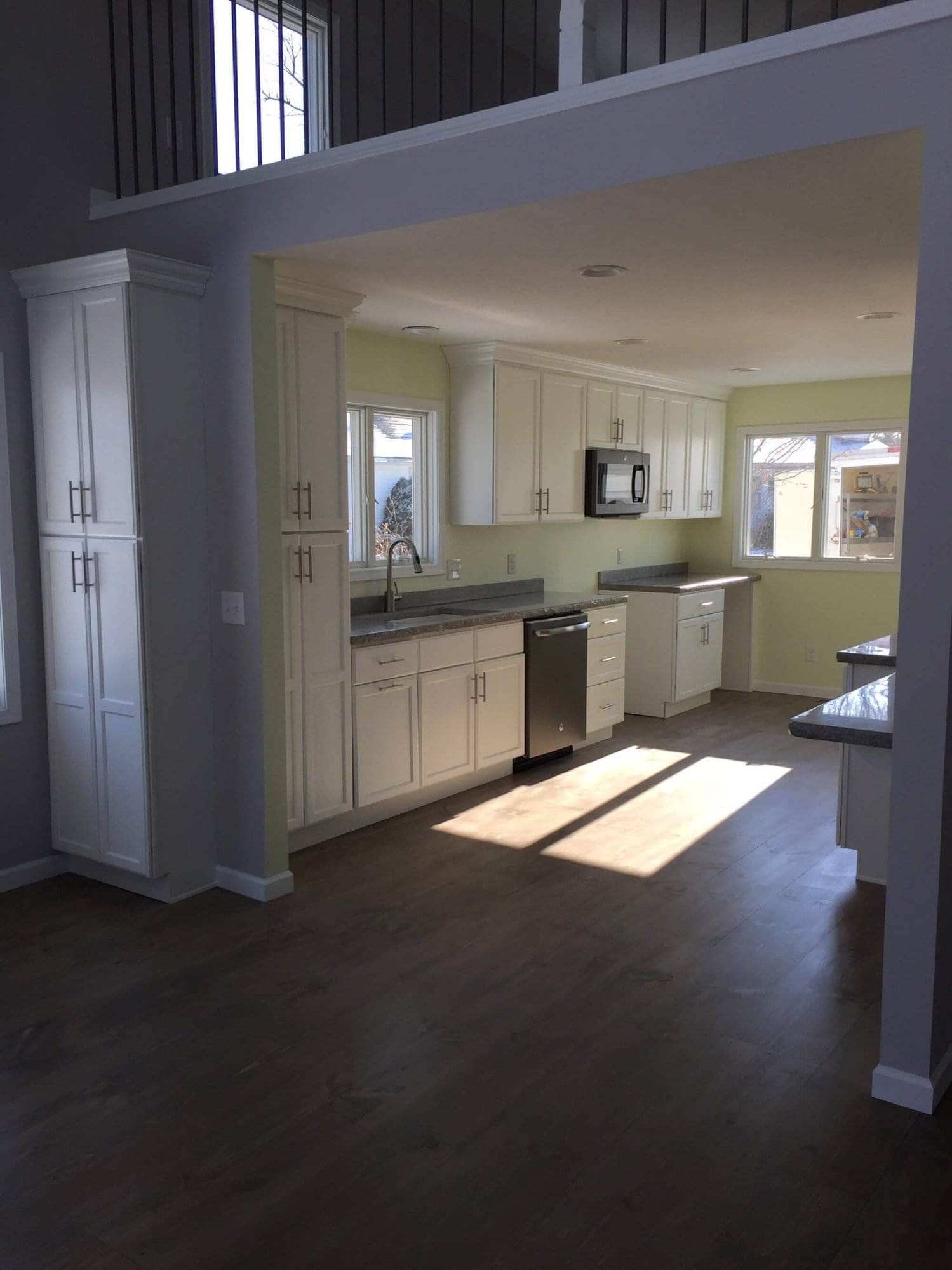 An empty kitchen with white cabinets and Huron hardwood floors.