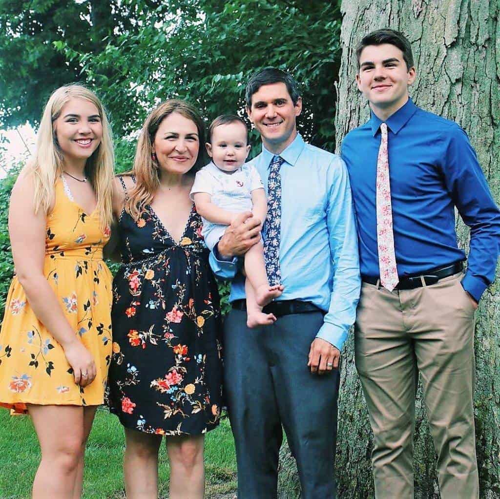 A family posing for a picture in front of an important tree.
