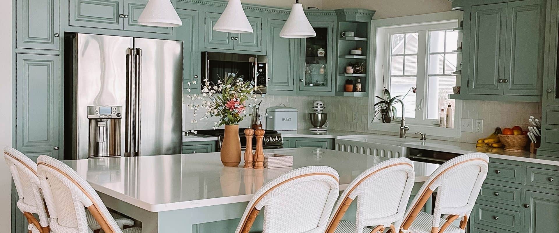 A kitchen with green cabinets and white counter tops.